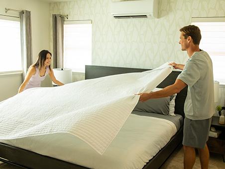 Couple making bed in master bedroom